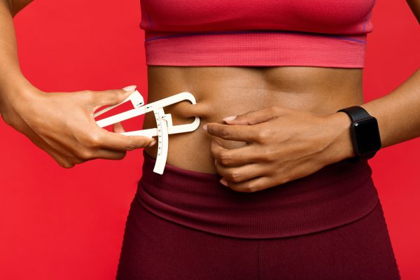 Woman measuring her body fat with body fat caliper