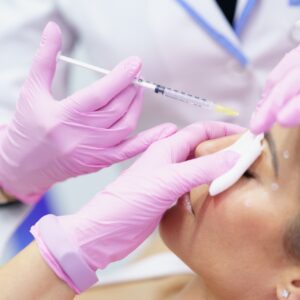 Aesthetic doctor injecting botox into the forehead of her middle-aged patient